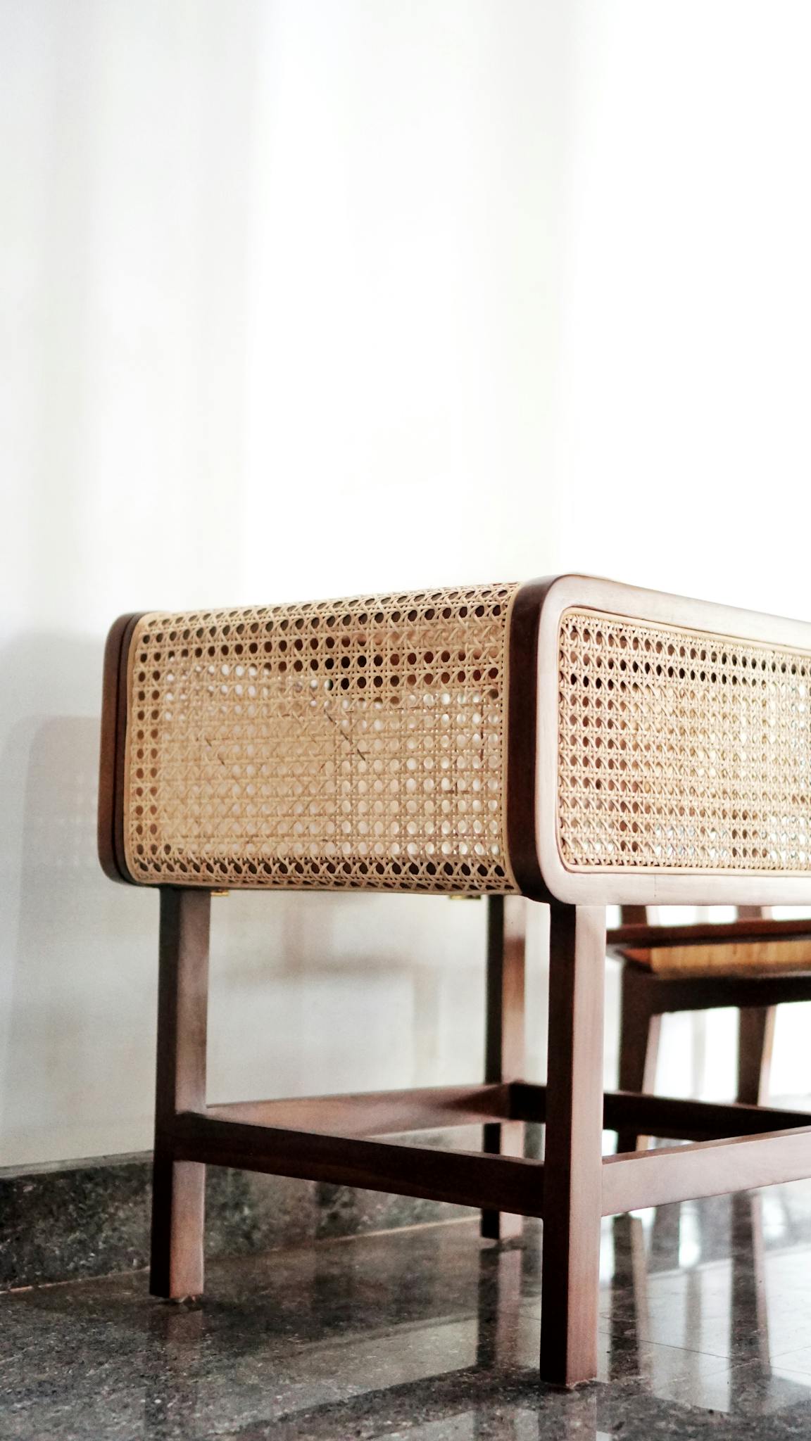Close-up of a modern rattan chair with wooden frame in a minimalist interior setting.