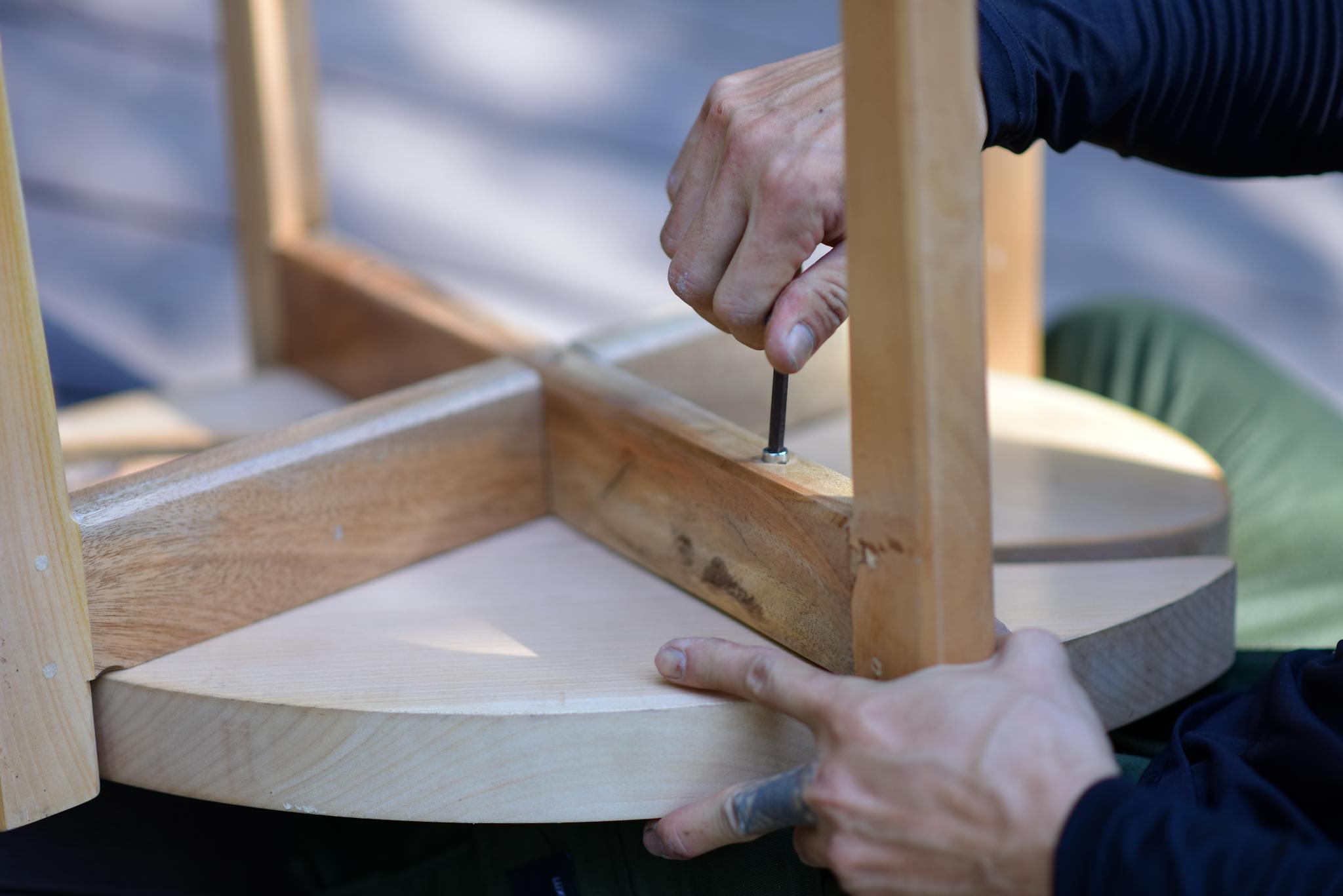 Hands assembling a wooden stool, highlighting craftsmanship and DIY spirit.